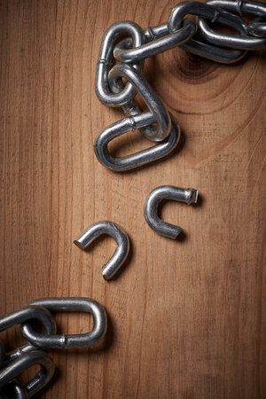 Freedom, security and broken metal chain for mental health, conflict and power on wood background. Steel, link and divorce from connection, stress and resilience in change, independence or liberationの写真素材