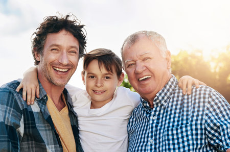 Father, child and grandfather with portrait in outdoor park for happiness, support and bonding together. Lens flare, family and generations of men with smile for legacy, morning walk or weekend breakの写真素材