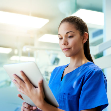 Woman, nurse and reading on tablet in hospital for medical research, telehealth and digital consultation. Medicine, professional and tech app in clinic for patient data, medicare schedule and resultsの写真素材