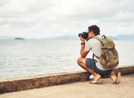 Man, camera and photography by sea as travel journalist for picture memory for creative, digital or lens. Male person, equipment and shoot in Thailand for nature trip as photographer, view or artistの写真素材