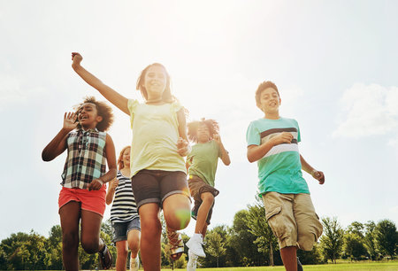 Happy children, friends and running with grass field in nature for fun, playful day or sunshine at...