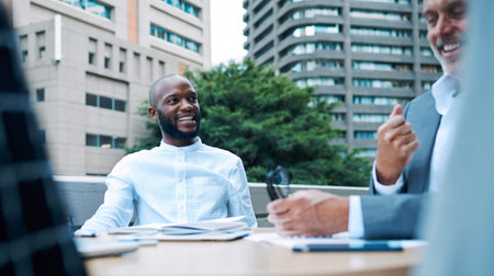 Happy, black man and entrepreneur in meeting outdoor, balcony and discussion for planning, research and ideas for project development. Smile, African and leader on rooftop, brainstorming and goalの写真素材