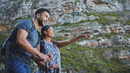 Couple, happy and pointing to mountain for hiking in forest with backpack, adventure and morning...