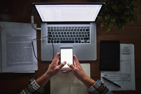 Person, programming and laptop with phone in office with typing for mockup space, coding and software script. Top view, technology expert and employee hands with programmer, it developer and notesの写真素材