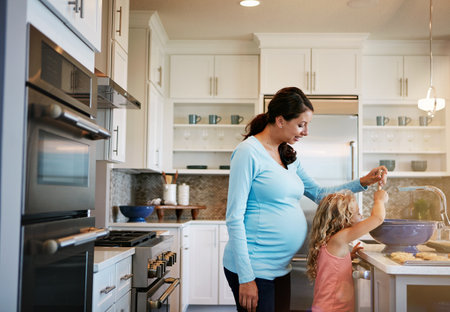 Mother, girl and cookies or helping with cooking for learning, bonding and preparation in kitchen with teaching. Family, woman and daughter with baking dessert, cake and sweet snack with fun in houseの写真素材