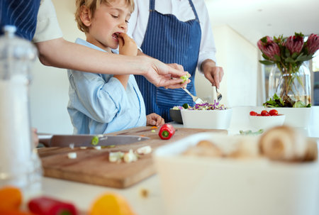 Family, boy and kitchen preparation in home, healthy food and chopping board with child eating for nutrition. Childhood development, growth and parents with ingredients, salad and culinary bondingの写真素材