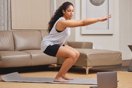 Online, pilates and girl with laptop to exercise in home with workout class on internet for fitness. Yoga, stretching and woman in apartment watch video on computer, streaming tutorial or trainingの写真素材