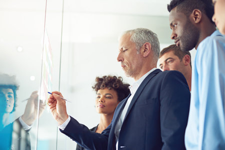 Glass wall, business people and brainstorming with problem solving, writing and meeting for collaboration. Group, employees and staff with ideas, support and cooperation with planning for projectの写真素材