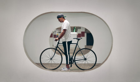 Architecture, bicycle and man with creativity, design and bike with thinking for ideas and vision. Transport, cool and trip or journey for adventure, travel and fitness with workout and hobbyの写真素材