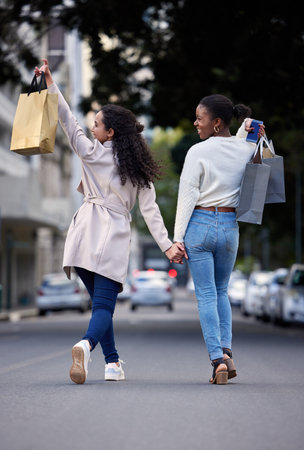 Woman, shopping bag and outside or back, sales and friends laughing or smile for retail deal or promotion. Discount, consumer and urban down town, shopper and buyers walking outside in streetの写真素材