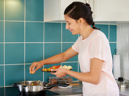 Cooking, stove and woman in kitchen with vegetables for meal prep for dinner, supper and lunch. Recipe, frying and happy person with ingredients in pan for wellness, nutrition and healthy eatingの写真素材