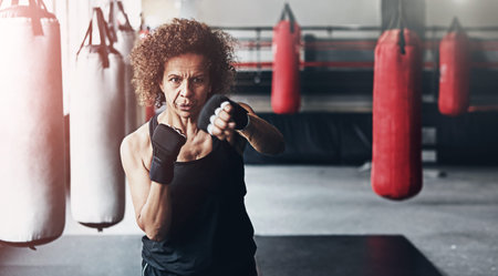 Fitness, punching bag and mature woman in gym for exercise, boxing challenge or competition...