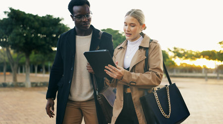 Partner, people and walking with tablet outdoor for commuting to work, discussion and online schedule. Happy, coworker and smile with career chat, networking and communication at park in New Yorkの写真素材