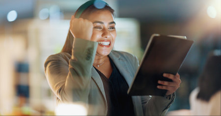 Fist, success and tablet with business woman in office for alert, good news or notification. Celebration, cheering and technology with professional employee in corporate workplace for email reactionの写真素材