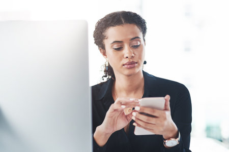 Woman, employee and smartphone at office browsing internet or for social media post and news update. Female person, computer and searching for online application, networking or communicationの写真素材