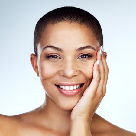 Happy, woman and skincare with hand on face for natural shine or glow for dermatology isolated in studio. Smile, female person or model and facial treatment for clear skin with white backgroundの写真素材