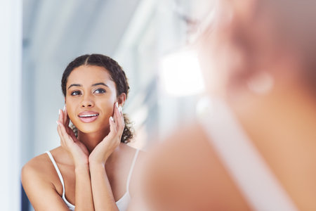 Home, mirror and woman in bathroom, wellness and cosmetics with grooming routine, treatment and skincare. Person, apartment and girl with confidence, reflection and beauty with dermatology and healthの写真素材