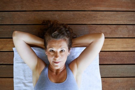 Woman, portrait and fitness on floor with top view for sit ups, exercise and core muscle workout on towel in gym. Yogi, person and relax after yoga class, training and healthy body with confidenceの写真素材