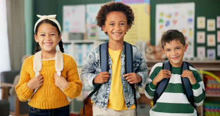 Children, face and smile as friends in classroom with backpack fr back to school, excited or education. Boys, girl and portrait at academy campus or lesson learning or knowledge, diversity or studentの写真素材