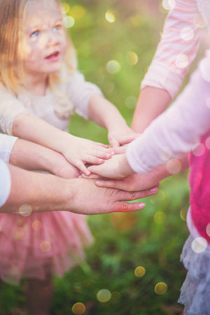 Kids, family and hands together for team, support and solidarity outdoor on bokeh in summer. Children, huddle and people in nature for community, success or connection for achievement celebrationの写真素材