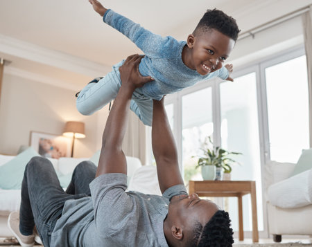 Dad, boy and smile with lifting in living room for bonding, love and trust for support and child development. Black people, parent and kid in home with laugh for comfort, care and playing for growthの写真素材