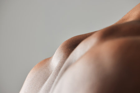 Back, closeup and topless man in studio with body health for fitness workout and exercise in gym. Bodybuilder, sports and grey background with muscle of model for training zoom for anatomy or growthの写真素材
