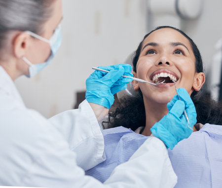 Dental checkup, women and dentist with tools, wellness and appointment for teeth whitening. People, professional and medical with patient in chair, equipment or remove plaque with gum disease or careの写真素材