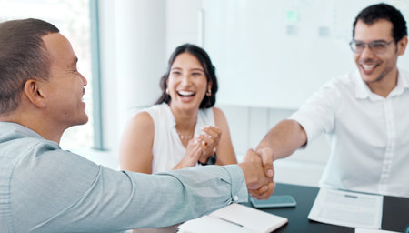 Handshake, people and business meeting with paperwork for partnership, agreement or review project. Design team, employees and happy client at table for briefing, deal or teamwork on proposalの写真素材