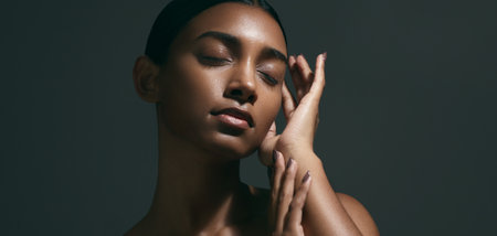 Beauty, sensual and face of woman in a studio with body care, wellness and health routine. Cosmetic, movement and portrait of an Indian female model with glowing skin treatment by a black background.の写真素材