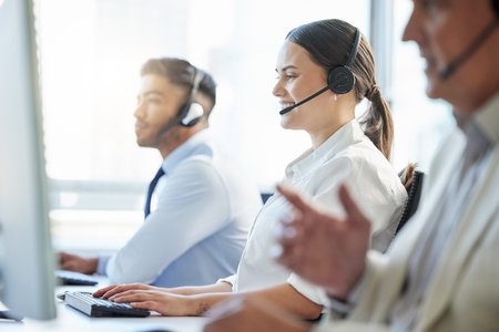 Call center, woman and smile with headphone, conversation and communication in workplace. Group, technology and telemarketing agent or team in office for consulting, customer service and supportの写真素材