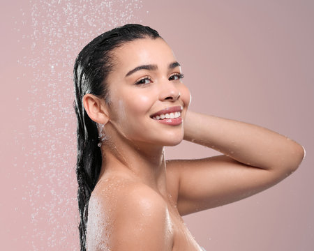 Portrait, cleaning and woman with water splash, wet and dermatology on studio background. Face, person and model with liquid, washing and shower with hygiene, wellness and smile with grooming routineの写真素材