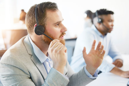 Man, listening and call centre with microphone in office for support, customer with faq in Europe. Male consultant, advice and help with headphones for telemarketing, service for debt review or loanの写真素材