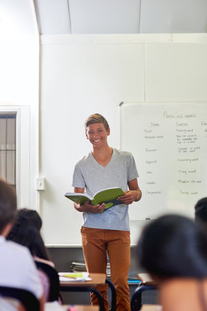 Classroom, young boy or learner portrait reading book for education, research and development of literacy skill. Presentation, student and novel for communication, studying and school project or oralの写真素材