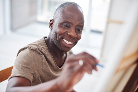 Black man, painting and art class or canvas easel with paintbrush for learning, hobby or creativity. Male person, smile and small business with talent inspiration for relaxing, workshop or pictureの写真素材