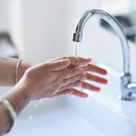 Water, person and hands in bathroom for hygiene, cleaning and protection from germs at home. Health awareness, washing in washroom and skincare with bacteria and cleanliness in house or at workの写真素材