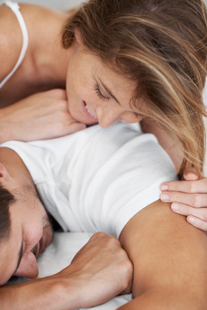 Smile, woman and man in bed with playful morning, peace and relax together for comfort in home. Romance, sleep and happy couple in bedroom on weekend with care, wellness and bonding in apartmentの写真素材