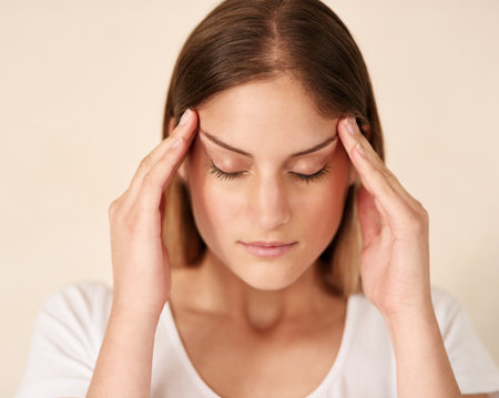 Headache, stress and face of woman with anxiety for crisis, burnout and frustrated for brain fog by wall background. Pain, temple massage and tired girl with migraine or dizzy for vertigo and healthの写真素材