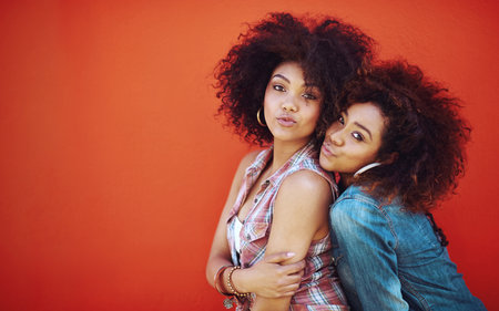 Girls, friends and portrait or fashion in studio with casual style, trendy outfit and mockup space on red background. Women, people and smile in city with streetwear, afro and pout in edgy clothesの写真素材