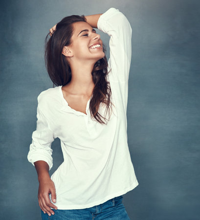 Woman, happy and laugh for fashion in studio background for style, trendy and outfit in gray backdrop. Female person, gen z and cheerful or excited for positive, cosmetic with pride or confidenceの写真素材