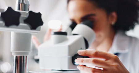 Hands, woman and scientist with microscope in lab for cancer treatment with pharmaceutical research. Person, study and innovation with drugs, medicine and dial for zoom, results and chemical solutionの写真素材
