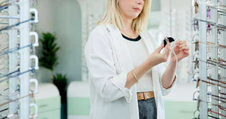 Hands, glasses and cloth at store for optometry, vision and wellness for eyesight, cleaning and dirt. Woman, customer and fabric for dust with inspection for eye care, health or style at retail shopの写真素材