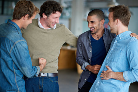 Office, friends or men with laugh after joke, comedy and remember funny memory with happiness. Creative team, business people and celebration with conversation, bonding and break to hangout togetherの写真素材