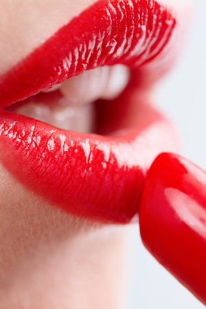 Woman, gloss and mouth for red lipstick in studio, makeup and cosmetics for care on white background. Female person and skincare or tube, grooming and application on lips for glow skin treatmentの写真素材
