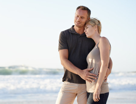 Couple, love and happy on beach with hug for bonding, honeymoon date or weekend holiday in Maldives. Man, woman and embrace with smile or care by water at sea for vacation, travel and adventureの写真素材