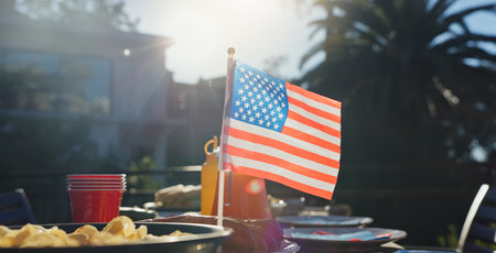 American flag, party and snacks outdoor for barbecue at reunion lunch for national independence day. Nature, terrace and chips on table for United states holiday event in backyard for country pride.の写真素材
