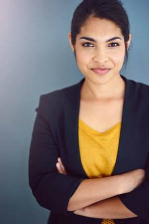 Business woman, portrait and crossed arms in studio on gray background for career, job and work. Employee, smile and confident accountant for pride, professional and corporate agenda with goalsの写真素材