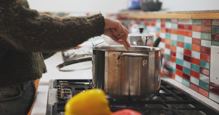 Hands, pot and cooking in kitchen on stove for healthy food, lunch or dinner with spoon and meal prep. Female person, oven and cookware in home for breakfast, eating and wellness with diet nutritionの写真素材
