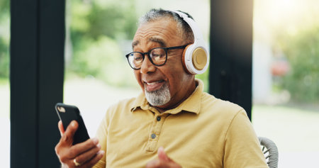 Elderly man, headphones and streaming music on phone, playlist and subscription to radio for audio. Senior person, laptop and reading news on mobile app, podcast and hip hop song for weekend funの写真素材