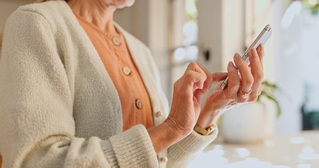Home, hand and senior woman with phone for network, communication and scroll on technology. House, internet and elderly person with smartphone for digital media, information and online news websiteの写真素材