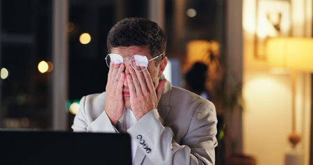 Businessman, headache and night with laptop in stress, debt or bankruptcy from burnout at office....